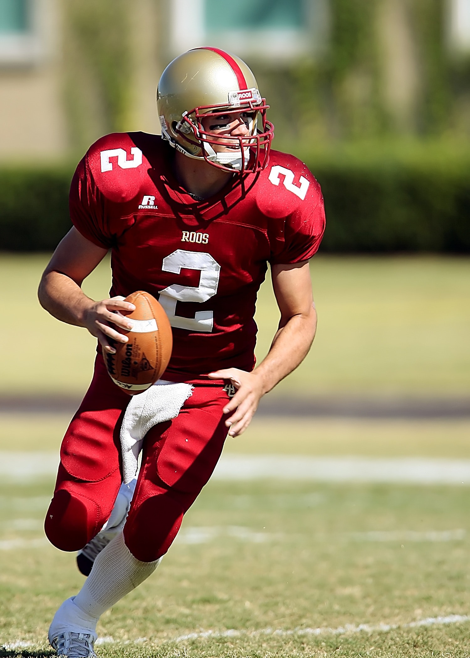 An American footballer in red merchandise running during a faceoff with ball in his right hand